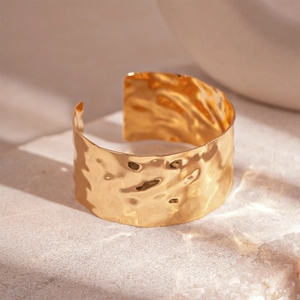 Modern wide hammered gold cuff bracelet with textured metallic fold design for women