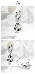 Detail of silver bell earrings with star cutouts and a clear zircon stone pendant