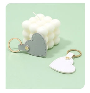 Close-up detail of gray and white heart-shaped leather keychains with golden metal rings