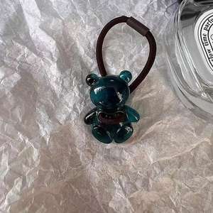 Détail d'un élastique à cheveux ours cyan translucide sur fond esthétique blanc