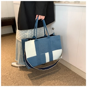 Detail of color-block patchwork tote with blue fabric texture and woven shoulder strap