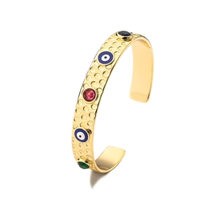 Macro-opname van vergulde open armband met kleurrijke stenen en evil eye emaille