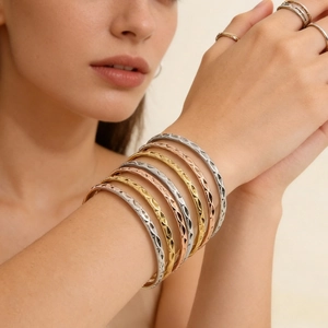Close-up of diamond quilted pattern bangles in gold, silver, and rose gold finish