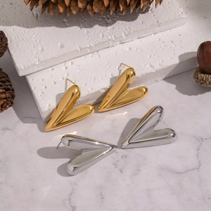 Minimalist gold and silver heart stud earrings on textured white stone display