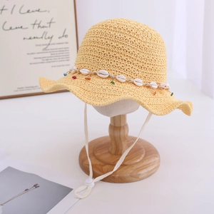Detail of yellow crochet sun hat with natural seashells and colorful beads decor