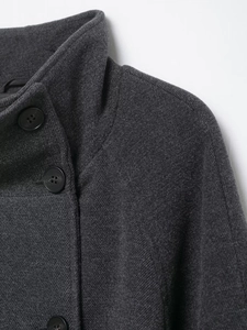 Close-up of charcoal gray wool coat fabric texture and black resin button detail
