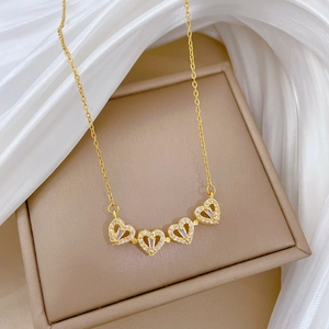 Detail of gold clover necklace with four hearts featuring crystal pavé and center stones