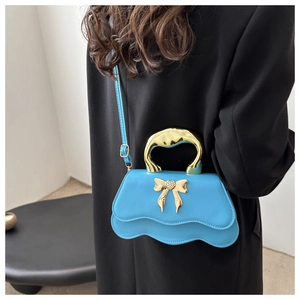 Close-up of blue PU leather bag featuring a gold bow accent and chunky metallic handle