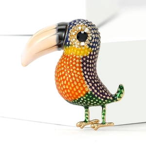 Macro shot of colorful enamel toucan brooch with golden base and black gemstone eye