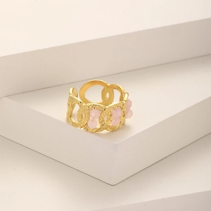Irregular gold-plated stainless steel chain ring with cluster of pink beads on a white pedestal