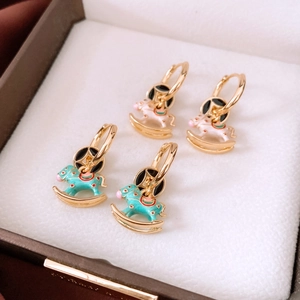 Detailed shot of 18K gold rocking horse earrings with white and teal enamel finish