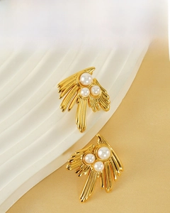 Macro detail of 18K gold plated swallow earrings featuring three pearls and radial design
