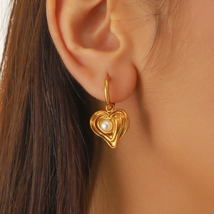 Fashion gold plated heart drop earrings with pearl inlay on female model for creative styling