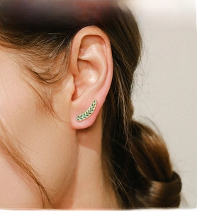Close-up of a s925 silver green enamel leaf ear crawler on a model's left ear