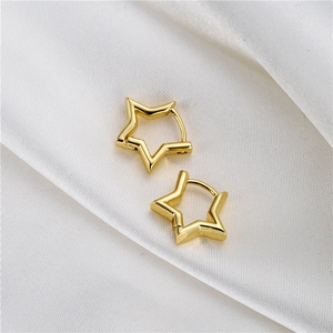 Detailed view of gold plated star shaped hoop earrings on elegant white silk fabric