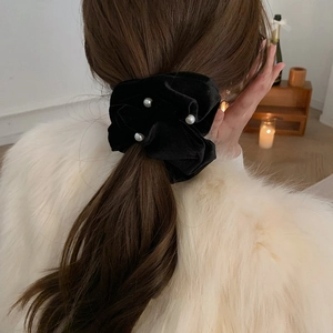 Elegant large pearl on black velvet scrunchie shown on a woman's hair in a back view