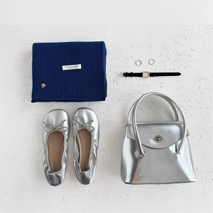 Dettaglio di una sciarpa in lana blu navy con etichetta e accessori moda argentati