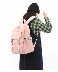 Rear view of a pink waterproof school backpack with cute bear patterns on a female model