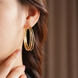 Three-layer gold textured hoop earrings with hammered metal detail on female model