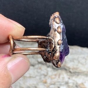Detailed shot of raw purple amethyst stone on an ornate copper adjustable ring