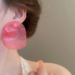 Close-up of translucent pink oversized resin earrings with textured finish on model