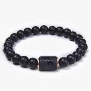 Detail of matte black onyx beads with rose gold Capricorn zodiac cylinder charm