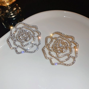 Elegant hollow flower brooch with diamonds in gold and silver finish on ceramic plate