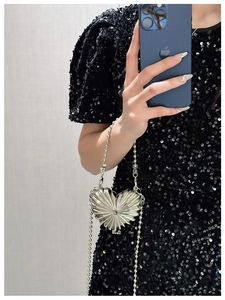 Detail of silver heart-shaped mini metal bag with pleated texture and pearl chain strap