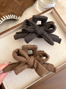 Détail de grandes pinces à cheveux à nœuds en tissu marron et beige sur un plateau esthétique