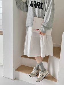 Close-up of white breathable mid-calf socks styled with grey sneakers and a long skirt