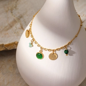 Dettaglio del bracciale boho placcato oro 18K con pietre verdi su un vaso di ceramica