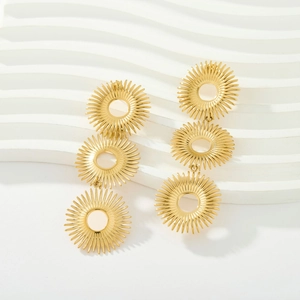 Detailed macro view of triple layered sunburst gold dangle earrings with brushed metal finish