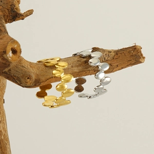 Detail of adjustable gold and silver wave rings displayed on textured wooden branch