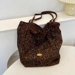 Detail of classic leopard print tote bag featuring a polished gold oval metal nameplate