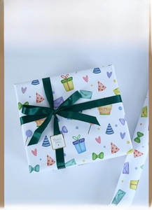 Détail de papier cadeau avec motifs festifs colorés, ruban vert et étiquette de merci