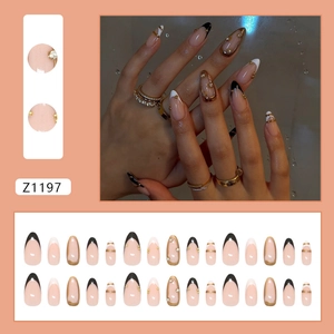 French almond press-on nails with black white tips, gold accents and rhinestone charms