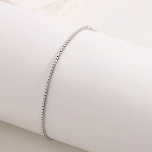 Détail du bracelet en acier titane argenté enroulé sur un support d'exposition blanc