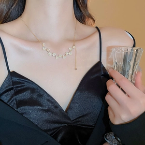Dettaglio della collana di fiori dorati con perle al collo, con delicati ciondoli floreali