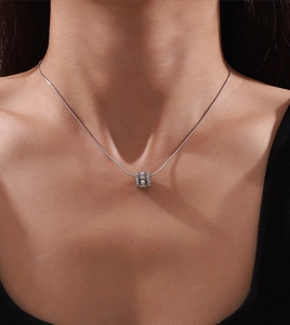 Detail of silver snake chain necklace with a cylindrical pavé cubic zirconia pendant