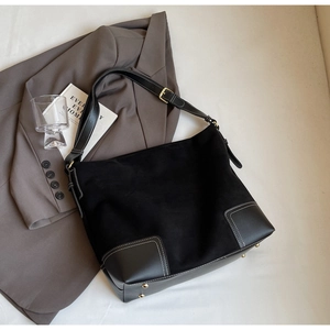 Detail of black suede tote bag with white contrast stitching and reinforced leather corners