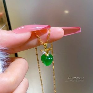 Macro shot of an apple-shaped opal pendant with gold-plated chain and zircon leaf detail