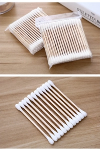 Detail view of double-tipped wooden cotton swabs with white buds in transparent polybag