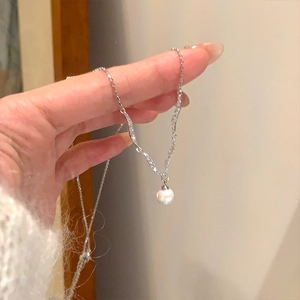 Minimalist silver necklace featuring a single white pearl pendant on a twisted chain