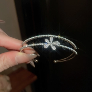 Detail of silver double-layered open bangle with cubic zirconia flower on the hand