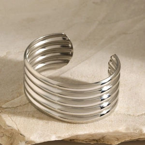 Detailed view of silver multi-layered wavy cuff bracelet on natural stone texture