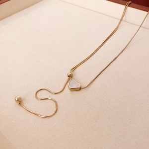 Détail du pendentif cœur doré avec nacre blanche sur une chaîne serpent sophistiquée