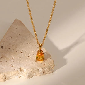 Detail of 18K gold-plated necklace with a yellow teardrop zircon on stone stand