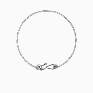 Macro shot of silver snake-shaped pendant with pavé diamonds on a minimalist chain