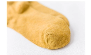 Macro detail of the yellow cotton sock toe showing high-quality knitted texture