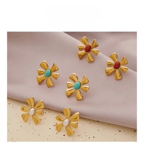 Detailed view of floral stud earrings set with pearl, turquoise, and coral stones